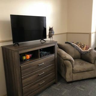 A cozy living room corner with a television on a dresser and an armchair nearby.