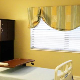 A hospital room with a bed and window covered by striped curtains.