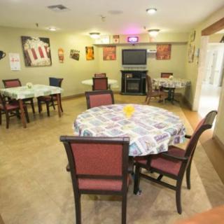 A cozy dining room with several tables and chairs, decorated with vibrant tablecloths and wall art.