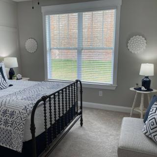 A modern bedroom with a black metal bed frame, geometric patterned bedding, and soft lighting from table lamps on either side of the bed.