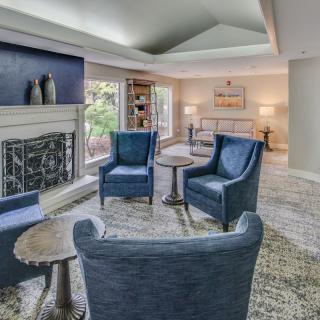 A cozy living room featuring a seating area with blue armchairs, a fireplace, and elegant decor.
