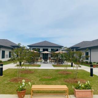 A tranquil courtyard with benches and potted plants, surrounded by modern buildings and outdoor seating.