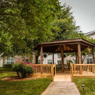 A serene gazebo surrounded by lush greenery in a residential garden.