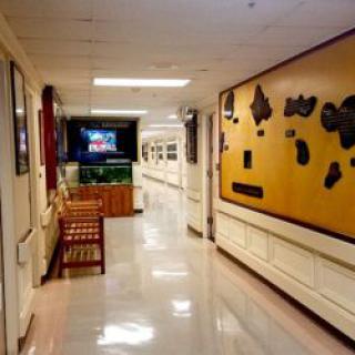 A well-lit hallway with artwork on the wall and a wooden bench.