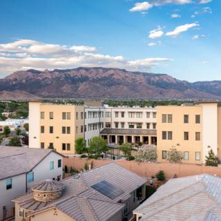 A picturesque view of a residential building set against a backdrop of majestic mountains under a clear sky.