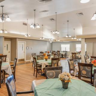 A spacious dining area with multiple tables and decorative lighting.