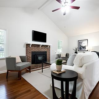 A modern living room with a fireplace, featuring a cozy sofa and armchair on a hardwood floor.
