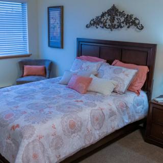 A cozy bedroom with a neatly made bed, decorative pillows, and stylish wall art.