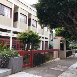 A modern school building with a tree-lined sidewalk.