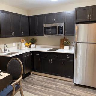 A modern kitchen with dark cabinets and stainless steel appliances.