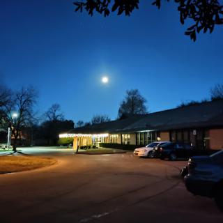 A serene night scene featuring a bright moon over a quiet parking area.