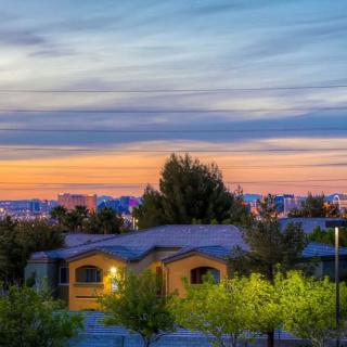 A serene suburban sunset with a view of houses and trees under a colorful sky.