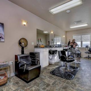 A cozy and well-lit salon/barber shop featuring styling chairs and mirrors.