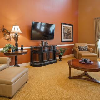 A cozy living room with orange walls, featuring a TV, comfortable seating, and tasteful decor.