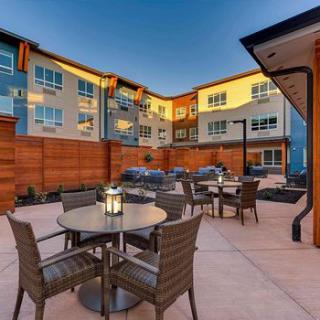 A modern apartment complex features a cozy outdoor seating area with tables and chairs under the evening sky.