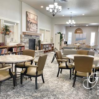 A well-furnished dining area with round tables and comfortable chairs, featuring elegant lighting and decor.