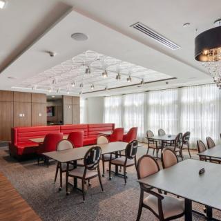 A modern restaurant interior featuring red booths and a variety of seating options.