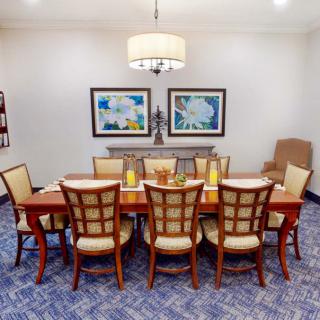 A well-decorated dining room featuring a large wooden table, matching chairs, a chandelier, and framed artwork on the wall.