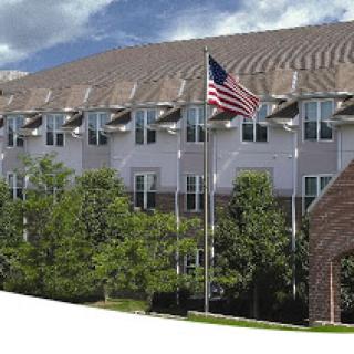 A view of a building featuring an American flag and surrounding greenery.