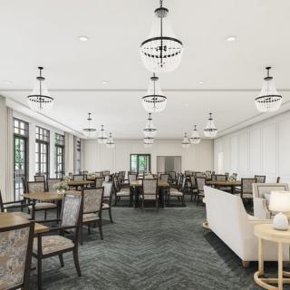 A spacious dining room with multiple tables and chairs, featuring elegant lighting fixtures and large windows.