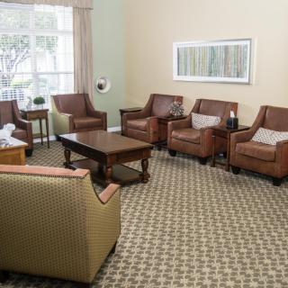 A cozy living room with several armchairs, sofas, and a coffee table arranged on a patterned carpet.