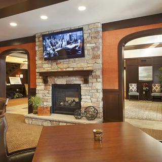 A cozy living room featuring a stone fireplace and a television mounted above it.