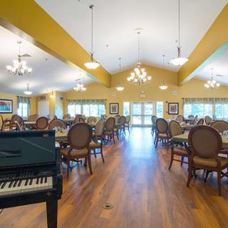 A spacious dining area featuring elegant chandeliers and a grand piano.