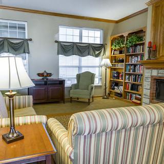 A cozy living room with striped furniture, a bookshelf filled with books, and warm lighting.