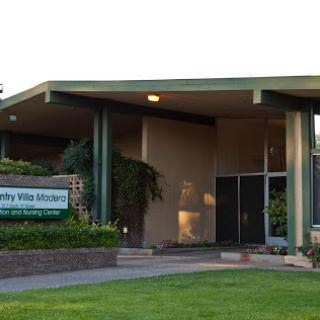 The entrance of a modern building surrounded by lush greenery.