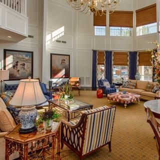 A spacious and elegantly furnished living room with large windows, a chandelier, and comfortable seating.