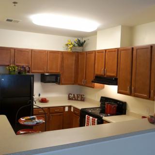 Modern apartment kitchen with wooden cabinets and black appliances.