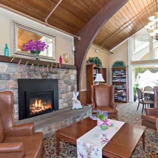 A cozy living room featuring a stone fireplace, leather chairs, and wood ceilings.