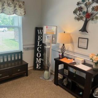 A cozy entryway with a 'Welcome' sign, a bench, and decorative elements.
