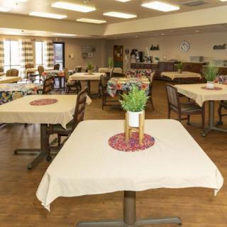 An indoor dining area with neatly arranged tables and chairs, decorated with potted plants.