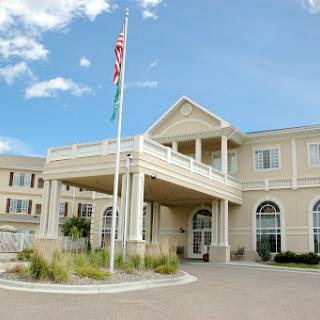 A welcoming entrance of a modern building featuring a flagpole and landscaped surroundings.