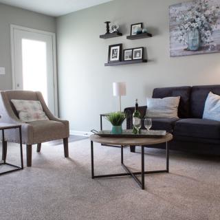 A modern living room with a sofa, armchair, and coffee table, decorated with minimalist elements.
