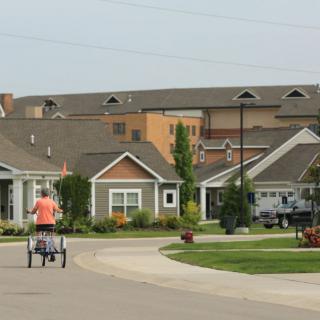 A quiet suburban neighborhood with houses and a person riding a bicycle on the street.