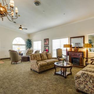A spacious living room with comfortable seating, a chandelier, and a fireplace.