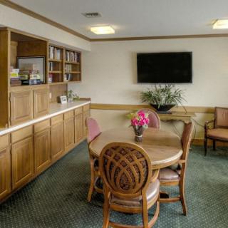 A cozy room featuring a round table with chairs, a television mounted on the wall, and a bookshelf in the corner.