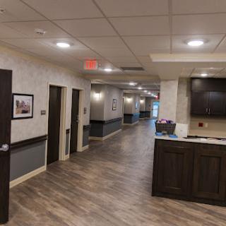 A spacious, well-lit hallway featuring a modern design with accessible rooms and a reception area.