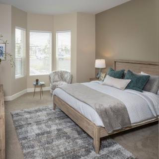 A modern bedroom with a cozy bed, stylish decor, and a large window.