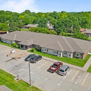 Aerial view of a suburban building with a parking lot and surrounding greenery.