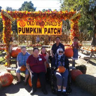 A joyful group of people enjoying a day at Old McDonald's Pumpkin Patch, surrounded by pumpkins and autumn decor.