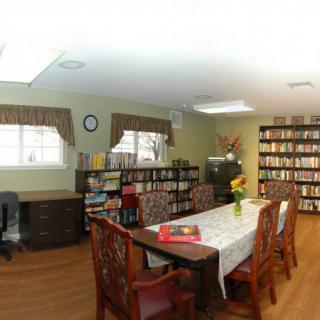 A cozy library with bookshelves, a large table for reading, and an office desk.