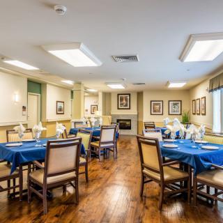 A well-arranged dining room featuring tables set with blue tablecloths and wooden chairs, creating a cozy and inviting atmosphere.