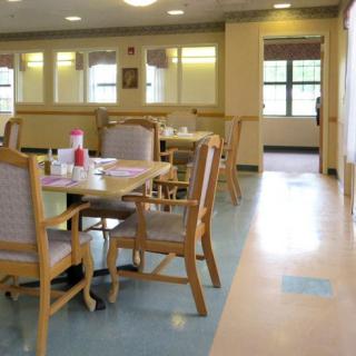 A bright and well-lit dining area with tables and chairs, featuring large windows.