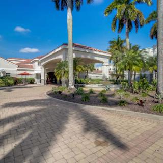 A welcoming hotel entrance surrounded by lush palm trees and a beautifully landscaped pathway.