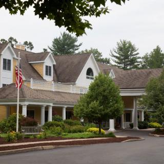 A picturesque residential building with an American flag and surrounding greenery.