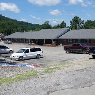 A view of a motel with parked vehicles under a clear blue sky.