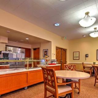 An interior view of an empty cafeteria with tables, chairs, and a food service counter.
